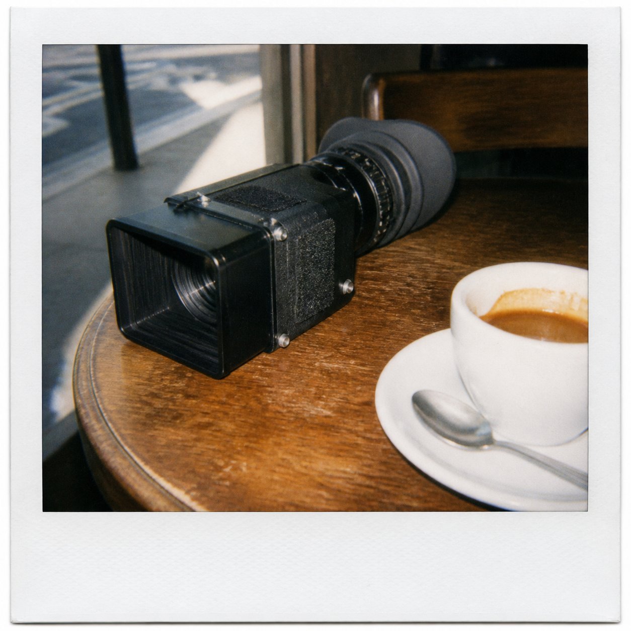 A director's viewfinder on a cafe table next to an espresso.