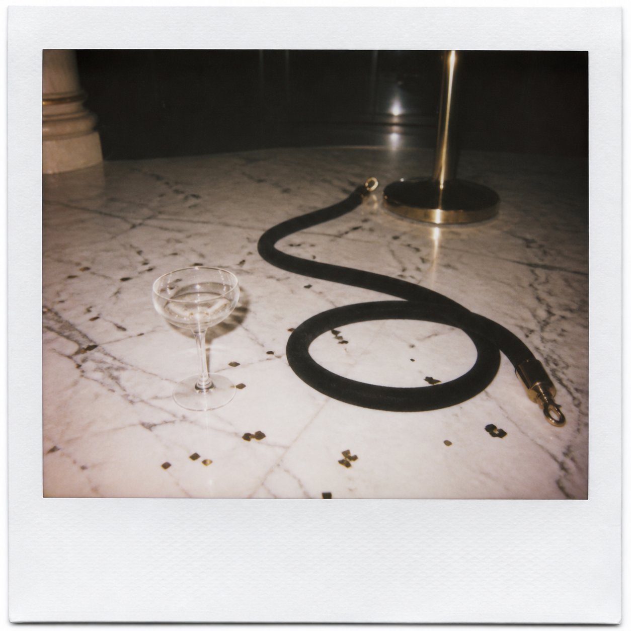 A velvet rope at a night event, champagne coupes behind.
