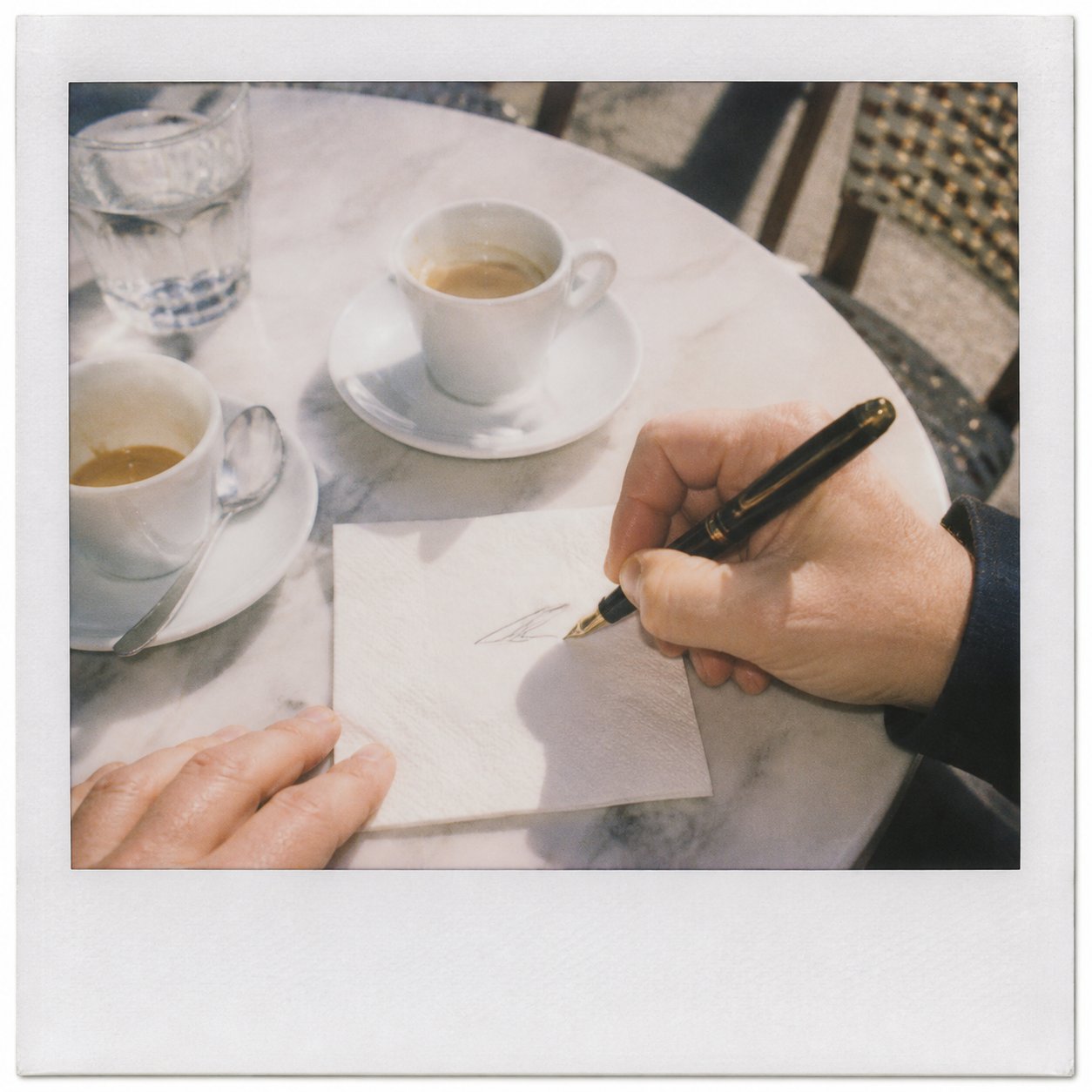 Two espressos and a fountain pen on a marble table.